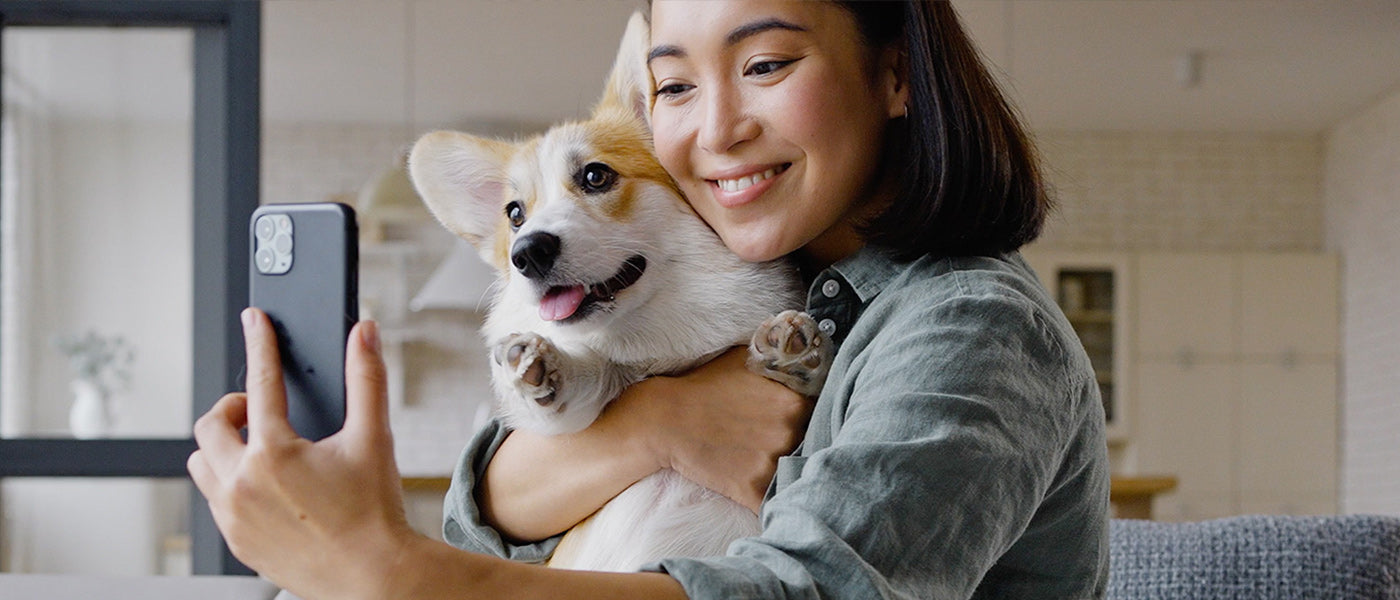 Woman holding a dog and taking a selfie in a home 