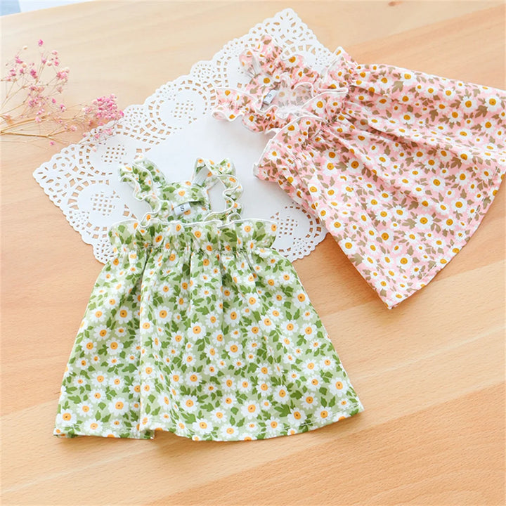 Two floral cat dresses on a wooden surface  