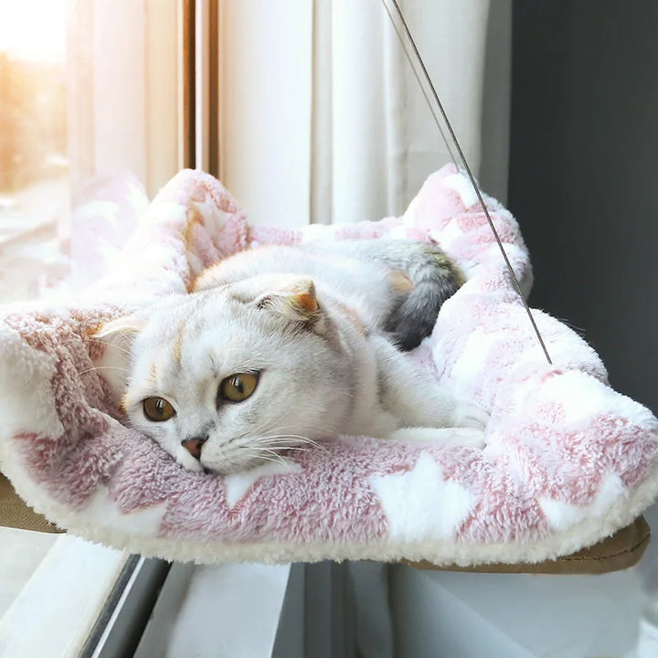 Cat lounging on a pink plush cat hammock.