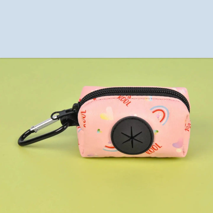 Pink Dog Poop Bag Holder with colorful designs and a black zipper on a green background