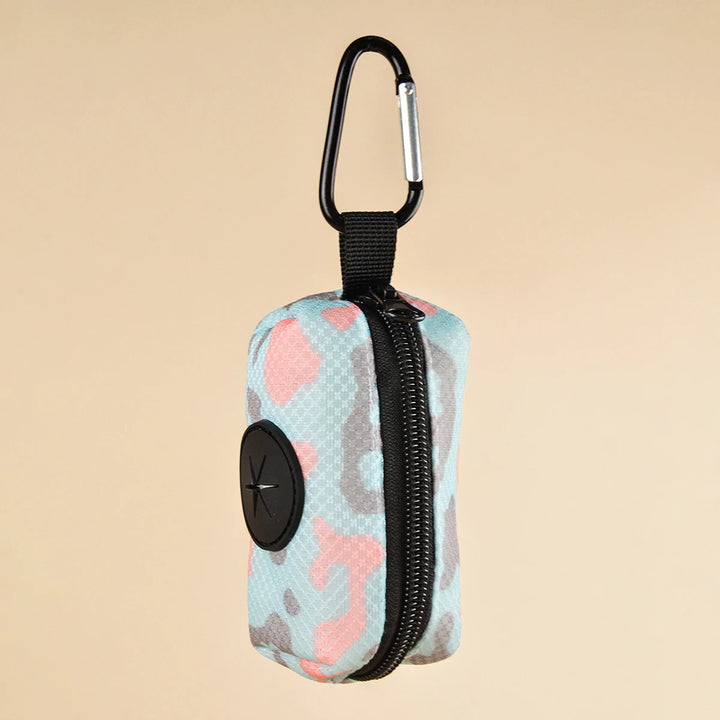 Camouflage-patterned kDog Poop Bag Holder with a carabiner on a beige background