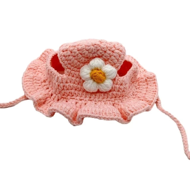 Pink crocheted pet hat with a white flower on a white background