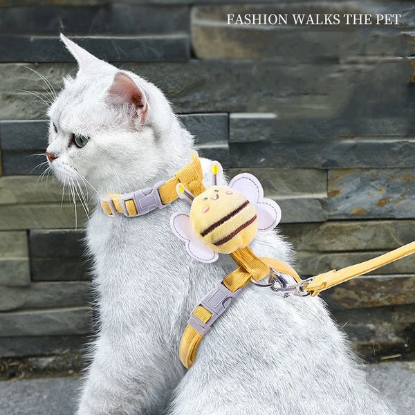 White cat wearing a yellow bee cat harness and leash